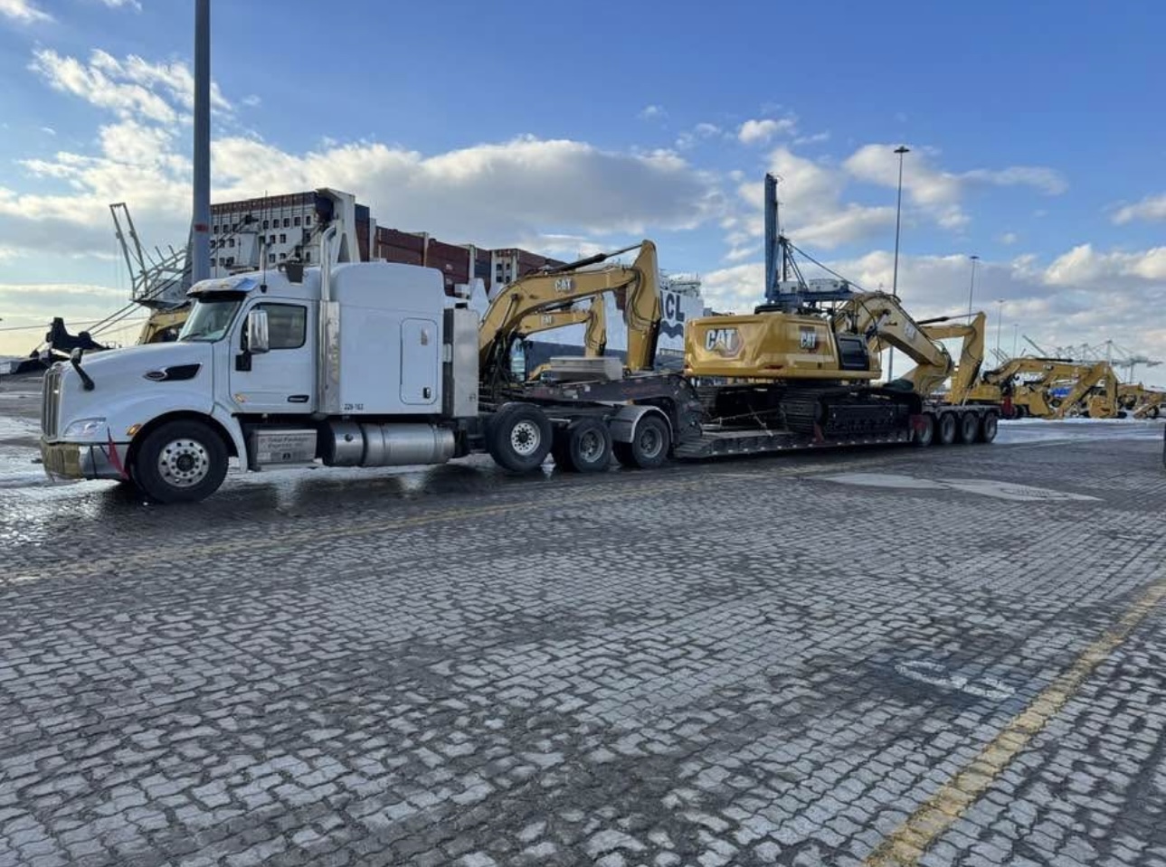 Peterbilt with lowboy hauling CAT excavator at port
